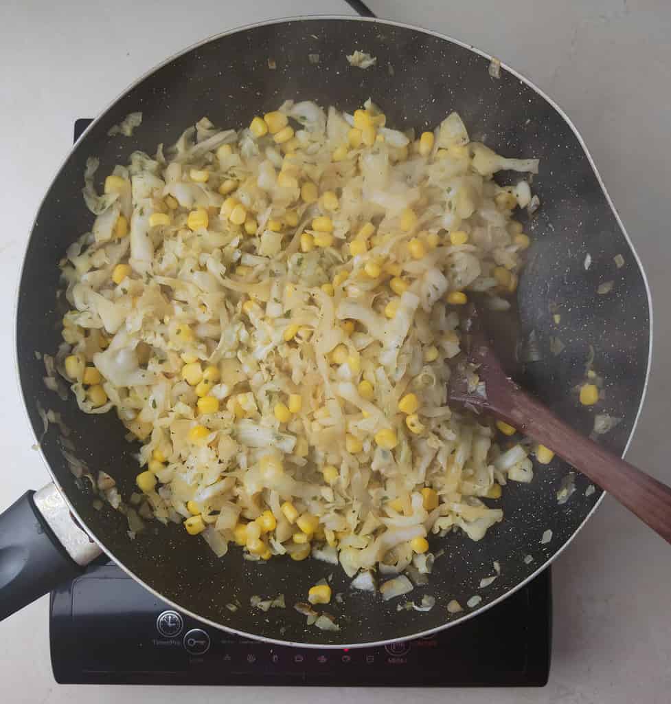 adding spices to the cabbage and sweet corn
